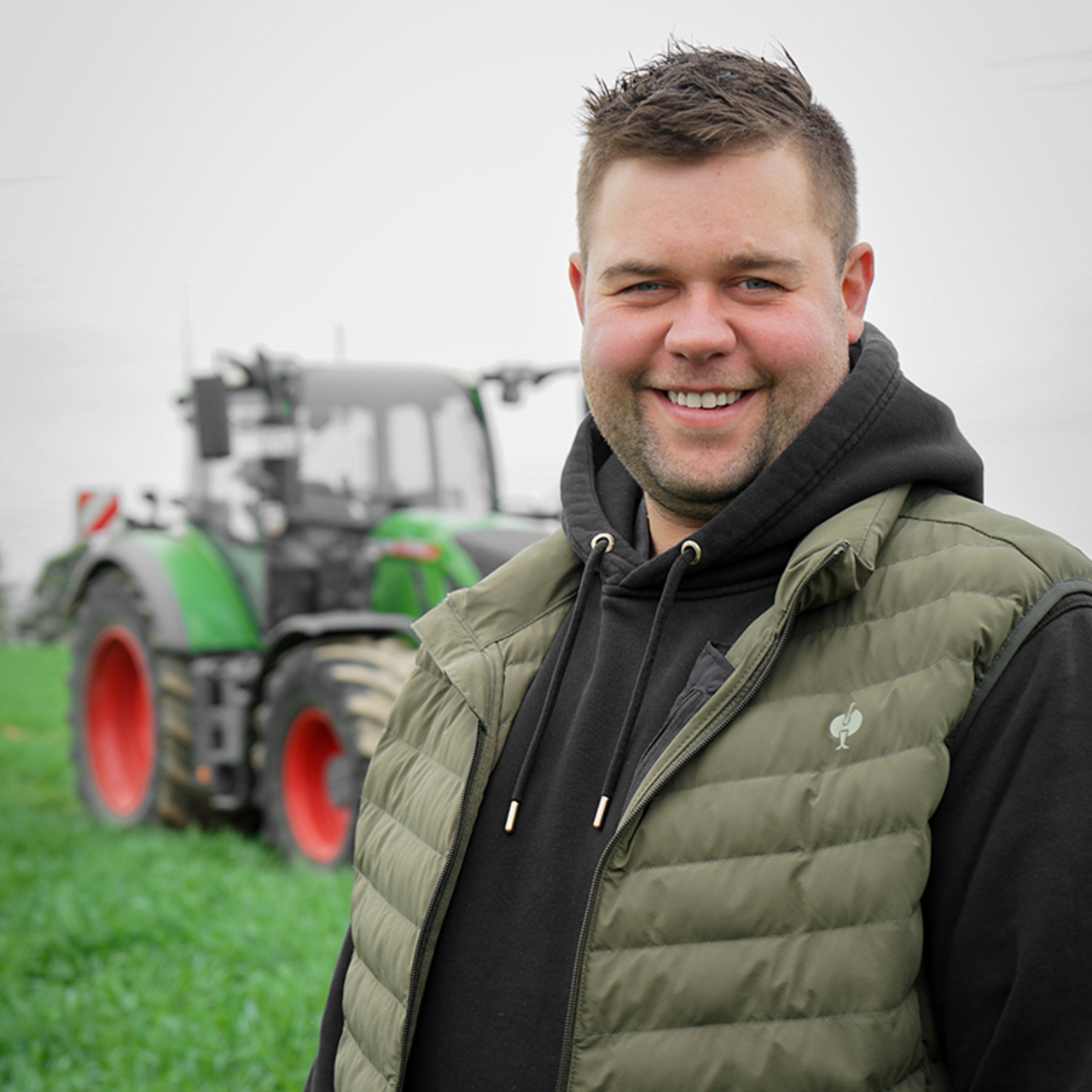 Partner-Landwirt Max Balzter auf einem Roggenfeld stehend - im Hintergrund ist ein Traktor zu sehen.