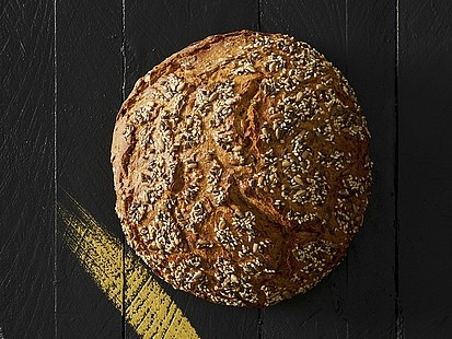 Das Rhöner Korn der Bäckerei Pappert erhält seinen besonderen Geschmack durch geröstete Saaten Das Rhöner Korn der Bäckerei Pappert auf einem schwarzem Holzhintergrund platziert.