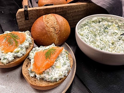Der Gurke-Dill-Aufstrich in einer Schale neben den Roggenbrötchen platziert.