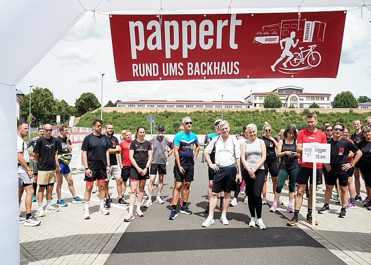 Das Bild zeigt Läufer, die unter einem Start- und Zielbogen auf den Start warten.
