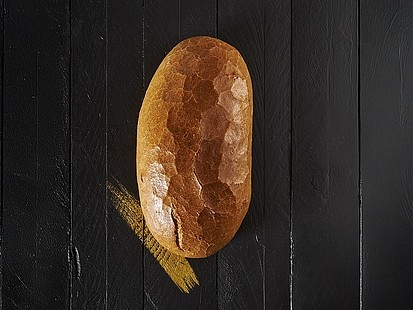 Das Nur der Bäckerei Pappert ist ein Weizenmischbrot nach Bauernart auf Stein gebacken Das Nur der Bäckerei Pappert auf einem schwarzem Holzhintergrund platziert.