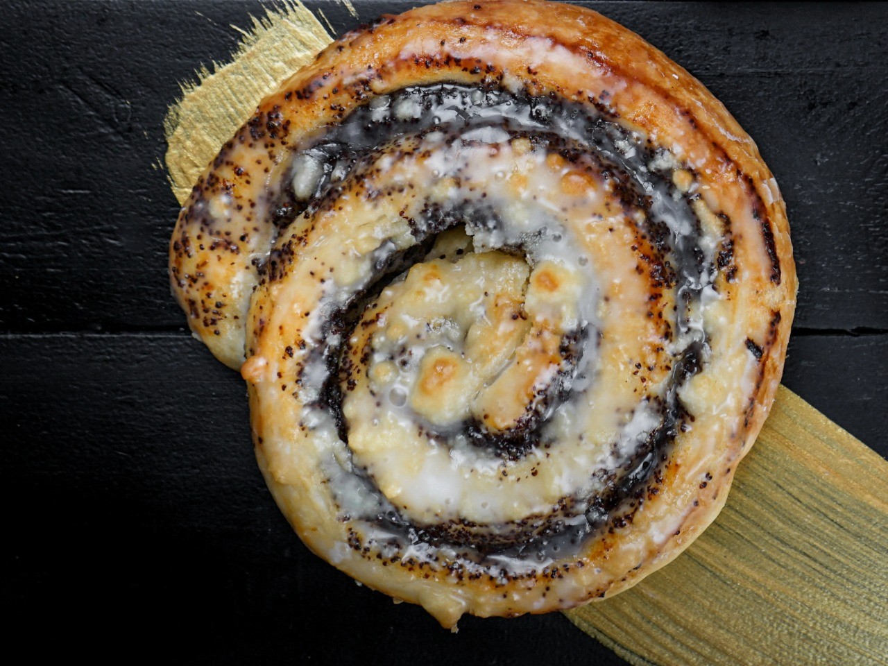 Die-Mohnschnecke-der-Bäckerei-Pappert-mit-aromatischer-Mohnfüllung-und-feinen-Butterstreuseln-auf-dunklem-Holzhintergrund