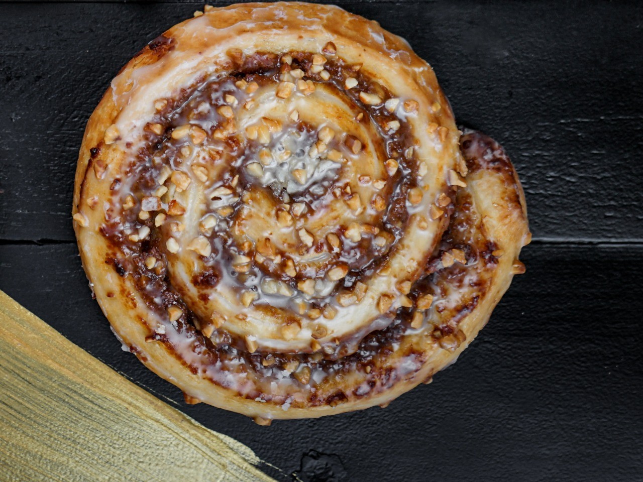 Die-Nussschnecke-der-Bäckerei-Pappert-aus-Butterplunderteig-mit-Nussfüllung-und-feinem-Butteraroma-auf-dunklem-Holzhintergrund